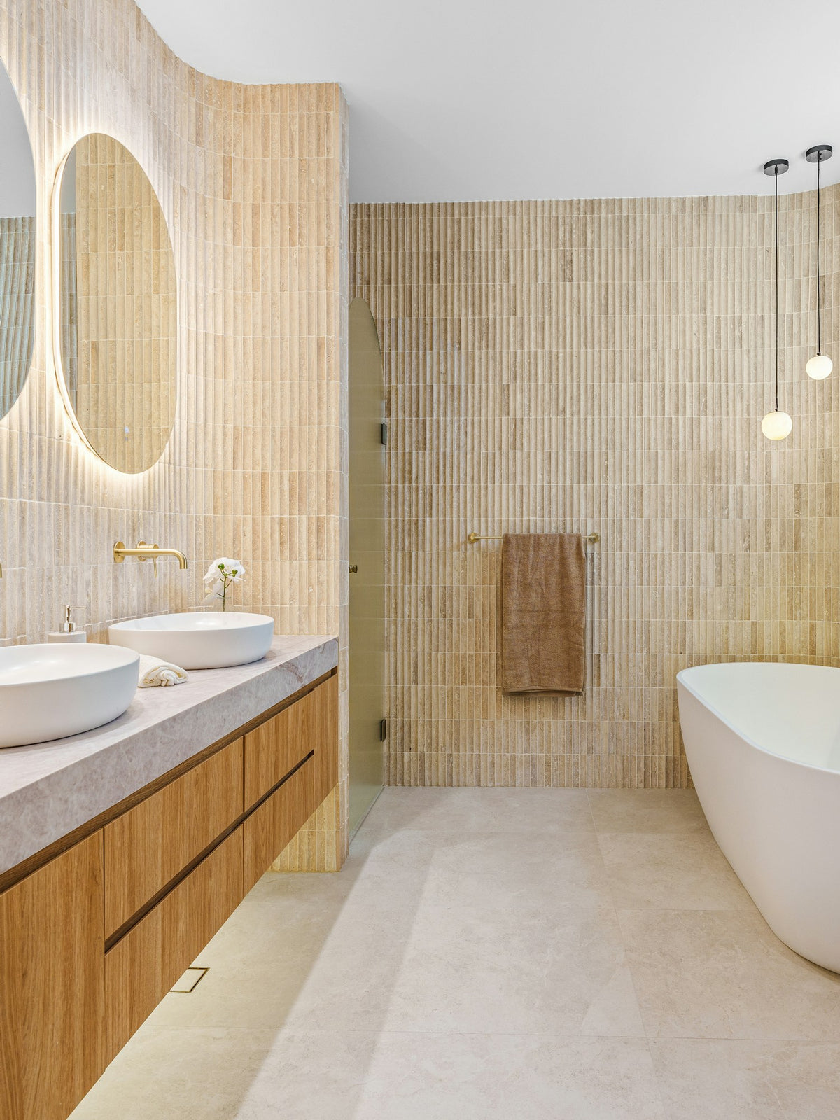 Salle de bain travertin avec vasques, robinetterie dorée et baignoire îlot – Valcourt Robinetterie (mobile)